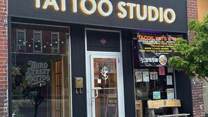 Ein Schaufenster mit einem Schild, auf dem 'Third Street Tattoo Studio' steht, und einem Ausstellungsfenster, das eine Tätowierung zeigt.