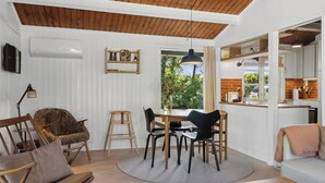 A dining area with a wooden table and chairs, a wooden ceiling, and a view of the outdoors. - Cozy holiday home with wood-fired tub and sauna (Rødby)