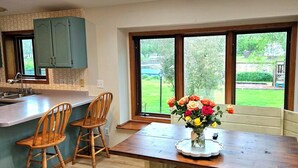 Une cuisine moderne avec un îlot central, des chaises en bois et une table à manger agrémentée d’un vase de fleurs.