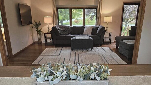 Un salon spacieux avec un grand canapé d’angle, une table basse agrémentée de plantes et un coin repas avec une table et des chaises en bois.