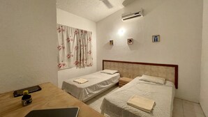 A bedroom with two single beds, a desk with a laptop, an air conditioner, and a ceiling fan. - Charming 2-bedroom house with Pool in gorgeous Puerto Escondido (Brisas de Zicatela)