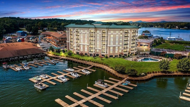 Un hotel con un edificio central, barcos amarrados y una piscina.