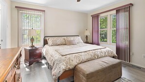 Ein Schlafzimmer mit einem Bett, einem Nachttisch, einer Kommode und einem Deckenventilator.
