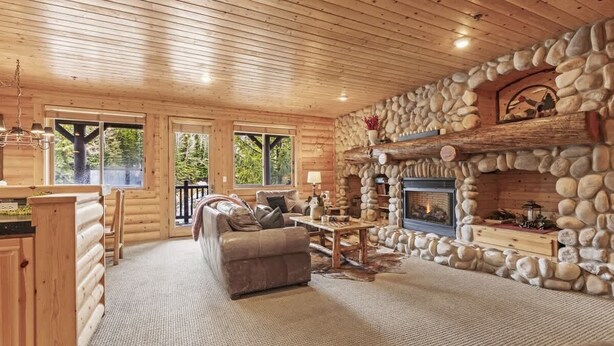 A log cabin interior with a stone fireplace, wooden furniture, and large windows. - Abode at Black Bear #207, hot tub, pool & gym, Deer Valley (Park City)