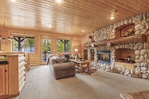 A log cabin interior with a stone fireplace, wooden furniture, and large windows. - Abode at Black Bear #207, hot tub, pool & gym, Deer Valley (Park City)