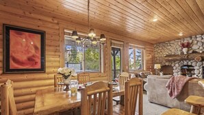 A wooden interior with a dining area, stone fireplace, and large windows. - Abode at Black Bear #207, hot tub, pool & gym, Deer Valley (Park City)