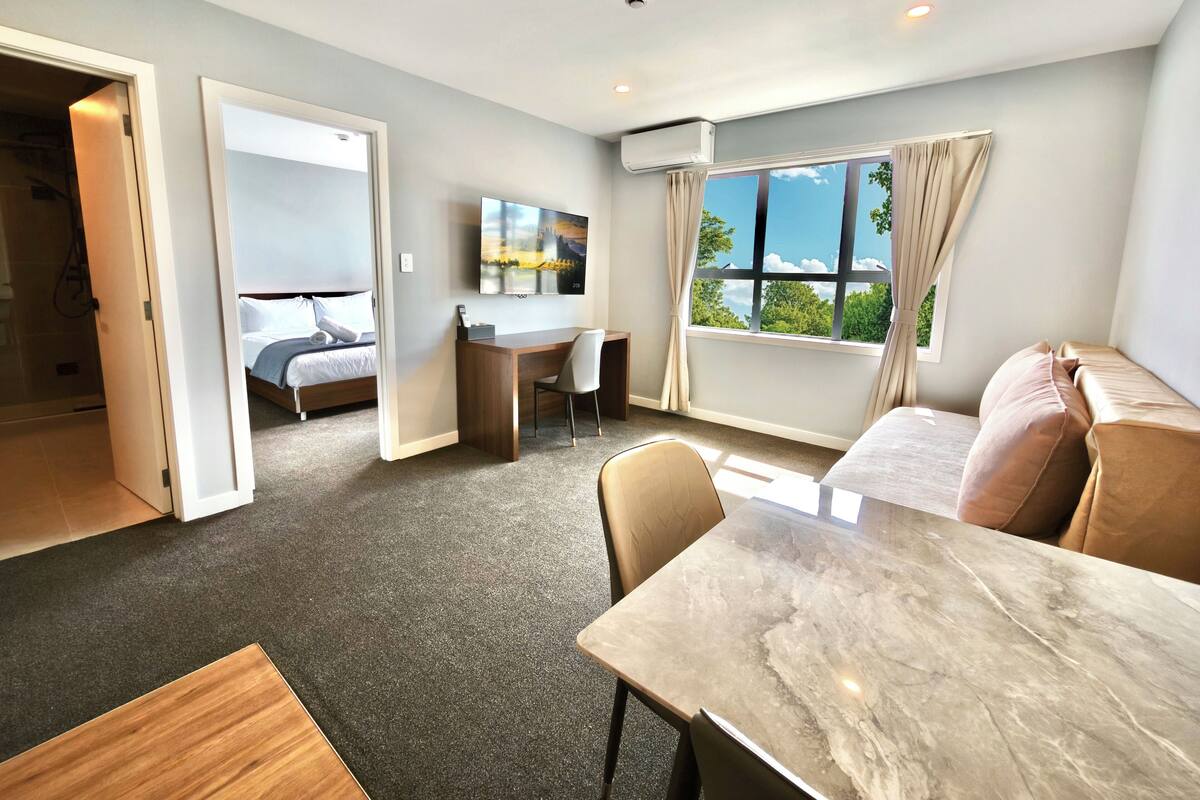 A hotel room with a bed, desk, and a view of the outdoors.