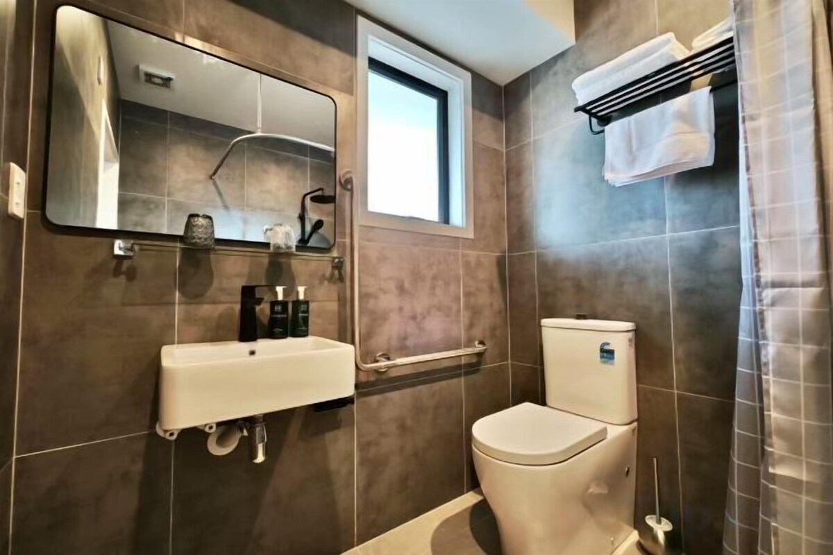 A bathroom with a toilet, sink, and a window.