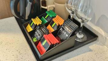 Un plateau avec une cafetière, deux verres et une boîte contenant un assortiment de sachets de thé.