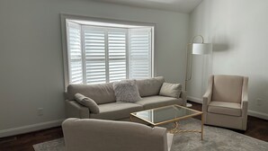 Una sala de estar con sofá, sillón y mesa de centro de vidrio.