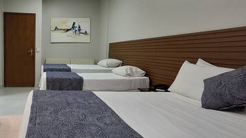 Quarto de hotel com duas camas, cabeceira de madeira e um quadro na parede.