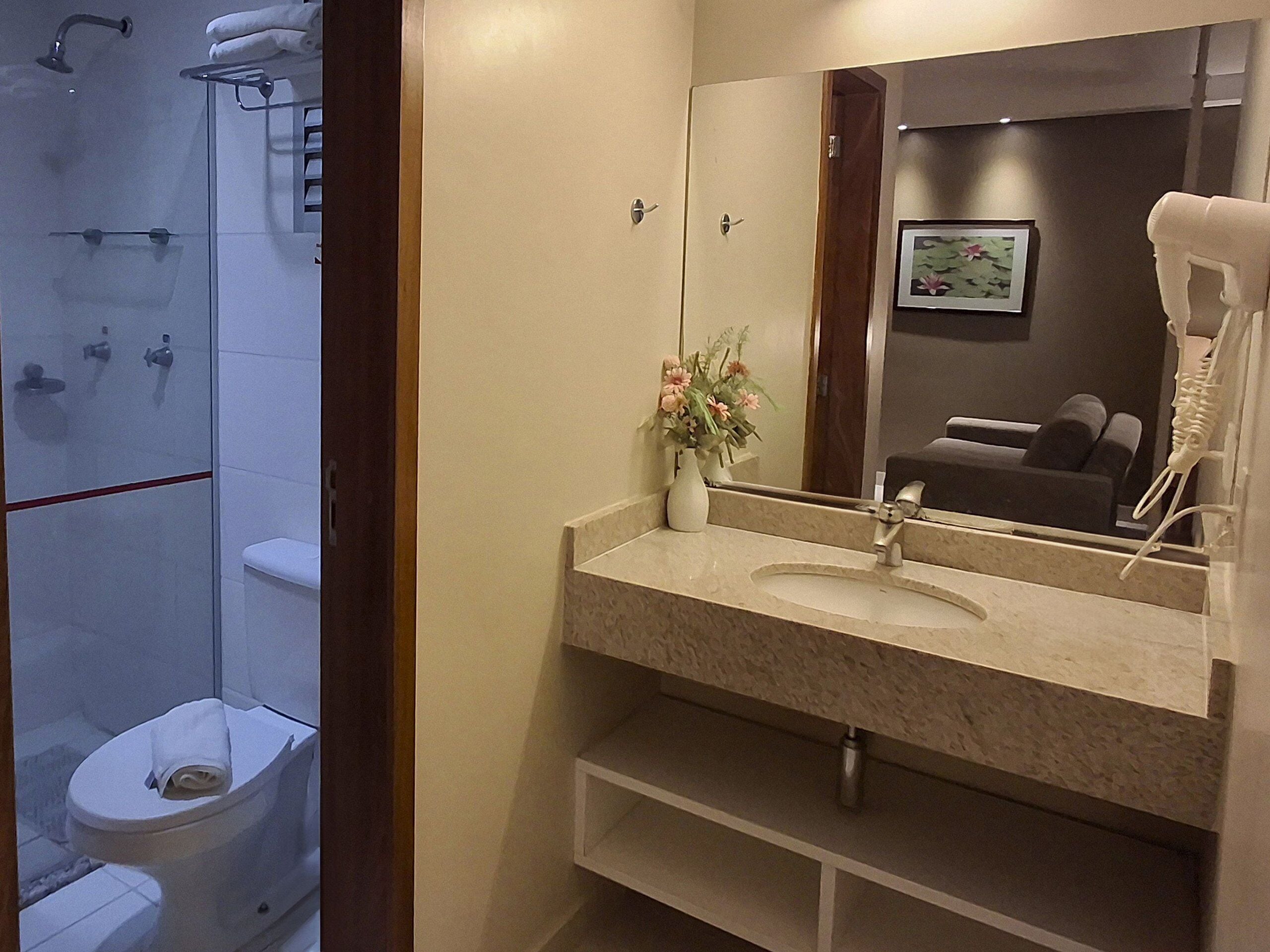 A bathroom with a toilet, shower, and sink.