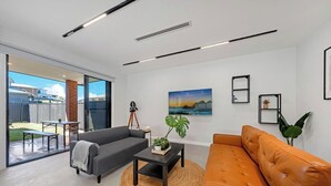 A modern living room with a grey sofa, an orange sofa, a coffee table, and a painting on the wall.