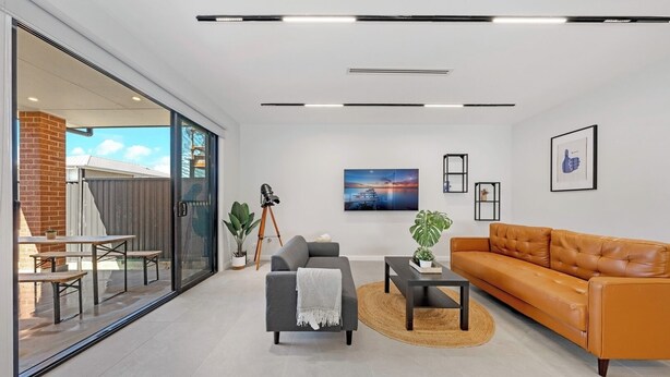 A modern living room with a sofa, coffee table, and a dining area with benches.