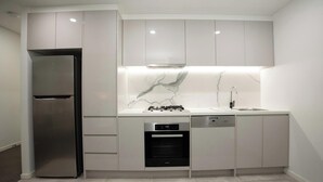 Uma cozinha moderna com frigorífico embutido, máquina de lavar loiça, fogão e pia.