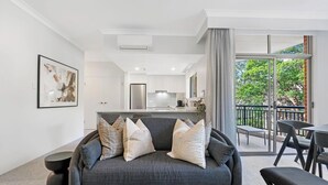 A modern living room with a grey sofa, a dining table, and a kitchen in the background. - KozyGuru | Camperdown | Cozy 2-Bed Apt + Parking (Camperdown)