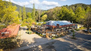 Un hotel con techo rojo, un espacio al aire libre cubierto y montañas al fondo.