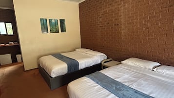 A hotel room with two beds, a brick accent wall, and a small window.