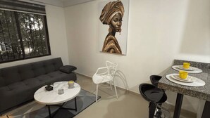 Un salon moderne avec un canapé gris, une table basse ronde et un coin repas doté d’un comptoir en granit et de tabourets de bar.