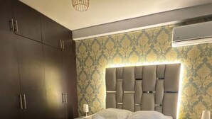 Une chambre à coucher moderne avec un grand lit, une armoire en bois foncé et un papier peint à motifs.