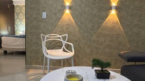 Un salon moderne avec une table basse en marbre, un fauteuil blanc et une petite plante en pot. Deux appliques murales sont fixées au mur.