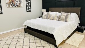 A bedroom with a large bed, a dark headboard, a patterned rug, and a painting on the wall. - Spacious 3-bedroom house with pool in a peaceful area in Bakersfield. (Bakersfield)