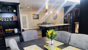 A dining area with a dark wooden table, grey upholstered chairs, and lemon-patterned placemats. - Spacious 3-bedroom house with pool in a peaceful area in Bakersfield. (Bakersfield)