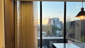 A modern kitchen with a large window, a dining area with chairs, and a view of the cityscape. - Alba by Pardela (Guadalajara)