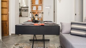 Ein Essbereich mit Tisch für zwei Personen, einer Couch und einem gemusterten Teppich.