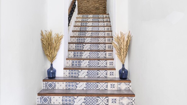 Eine Treppe mit gemusterten Fliesen und zwei Vasen mit Trockenpflanzen auf den Stufen.