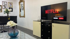 Una sala de estar moderna con un televisor de pantalla plana grande que muestra 'NETFLIX' y una oferta de 'Planes desde 6,99 € al mes'.