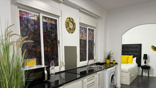 Una cocina moderna con armarios blancos, encimera negra y lavavajillas Corberda.