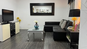 Una sala de estar moderna con una televisión de pantalla plana, un sofá, una mesa de centro y un cuadro enmarcado en la pared.