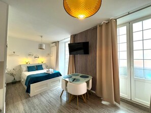 Een moderne hotelkamer met een bed, een televisie, een tafeltje en een raam met gordijnen.