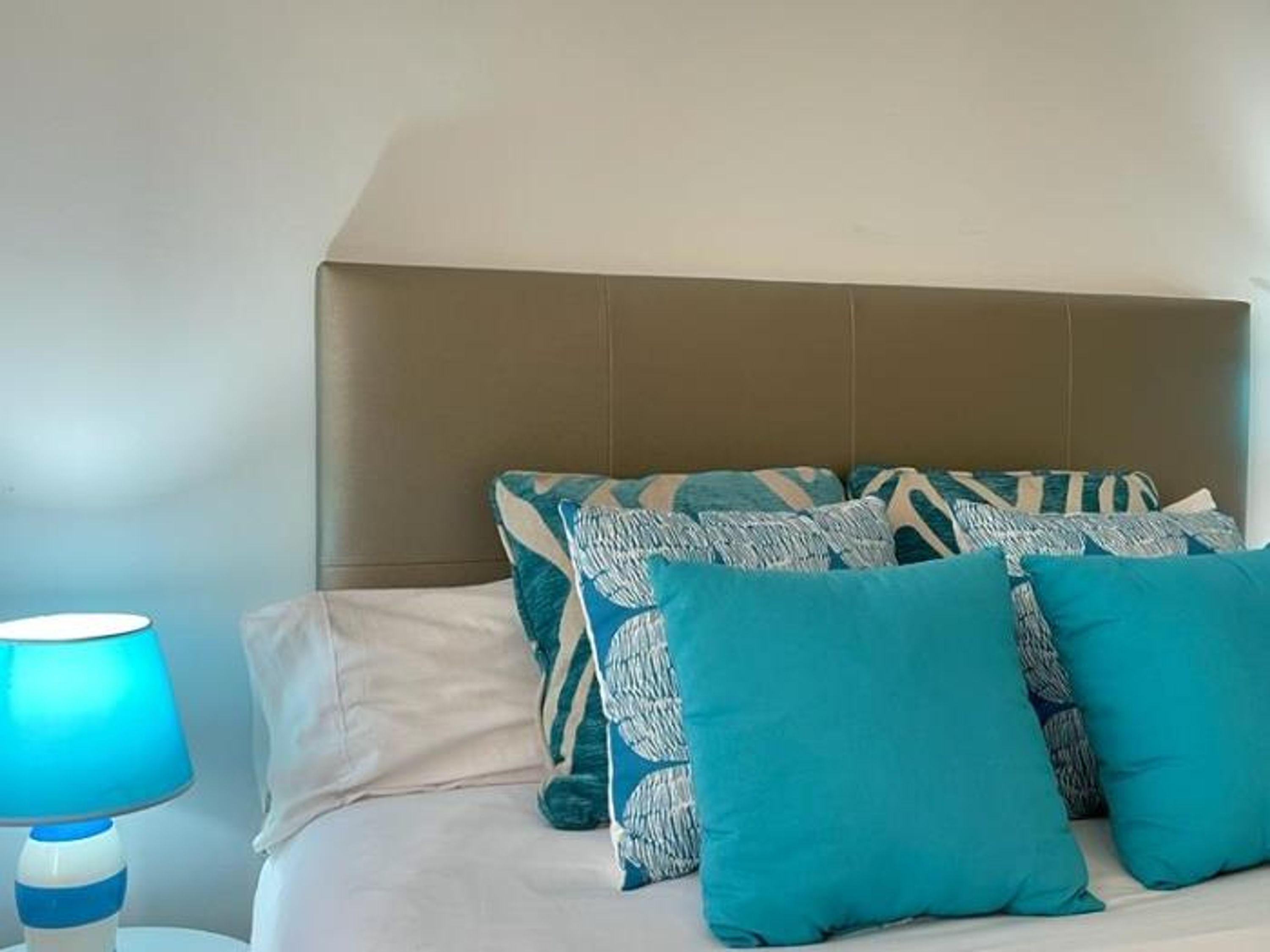 Un dormitorio con una cama, un cabecero y una lámpara de noche.