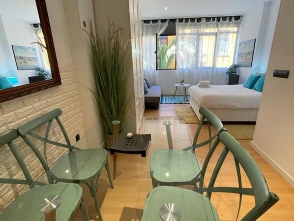 A modern hotel room with a bed, a small seating area with chairs, a potted plant, and a view of the outside. - El Oasis de los M Rtires (Málaga)