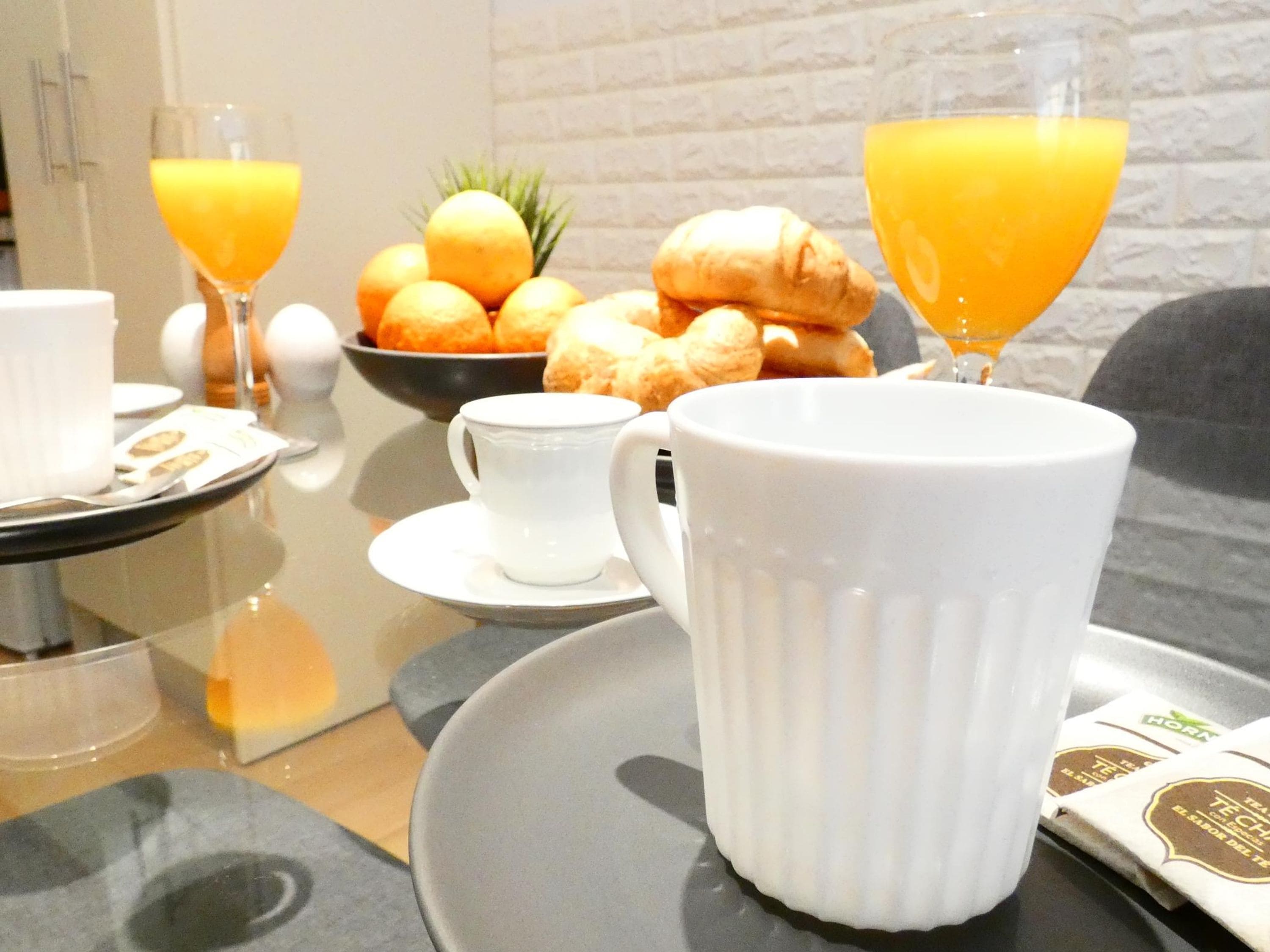 Een ontbijttafel met croissants, sinaasappels en sinaasappel sap.