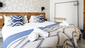 A hotel room with a wooden headboard, a large bed with patterned bedding, a bedside table, and a wall-mounted TV. - 7 Condes 4 (Málaga)