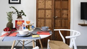 A dining area with a table set for two, a wooden door, and a framed picture on the wall. - 7 Condes 4 (Málaga)