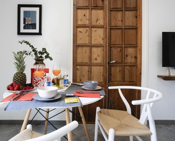 A dining area with a table set for two, a wooden door, and a framed picture on the wall. - 7 Condes 4 (Málaga)