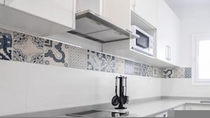 A modern kitchen with white cabinets, a patterned backsplash, and a microwave. - 7 Condes 4 (Málaga)