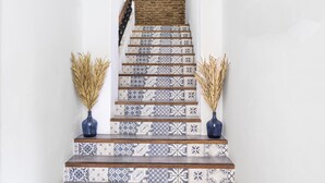 Eine Treppe mit gemusterten Fliesen und zwei Vasen mit Trockenpflanzen auf den Stufen.