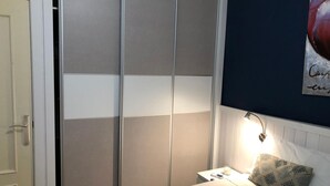A bedroom with a bed, a nightstand, a lamp, a wall with a poster, and a door. - Santelmo 16 (Málaga)