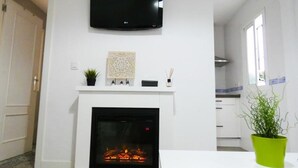 A modern living room with a fireplace, a mounted TV, and a potted plant. - Santelmo 16 (Málaga)
