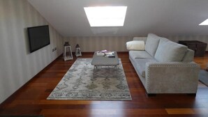 Una sala de estar con un sofá, una mesa de centro, un televisor de pantalla plana y dos lámparas de pared.