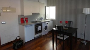 Una cocina funcional con lavadora, una mesa de comedor con sillas y un ventanal que proporciona luz natural.