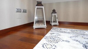 Una habitación con piso de madera, un tapete estampado y dos faroles blancos.