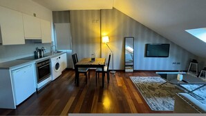 Una cocina compacta con comedor, lavadora y televisor montado en la pared.