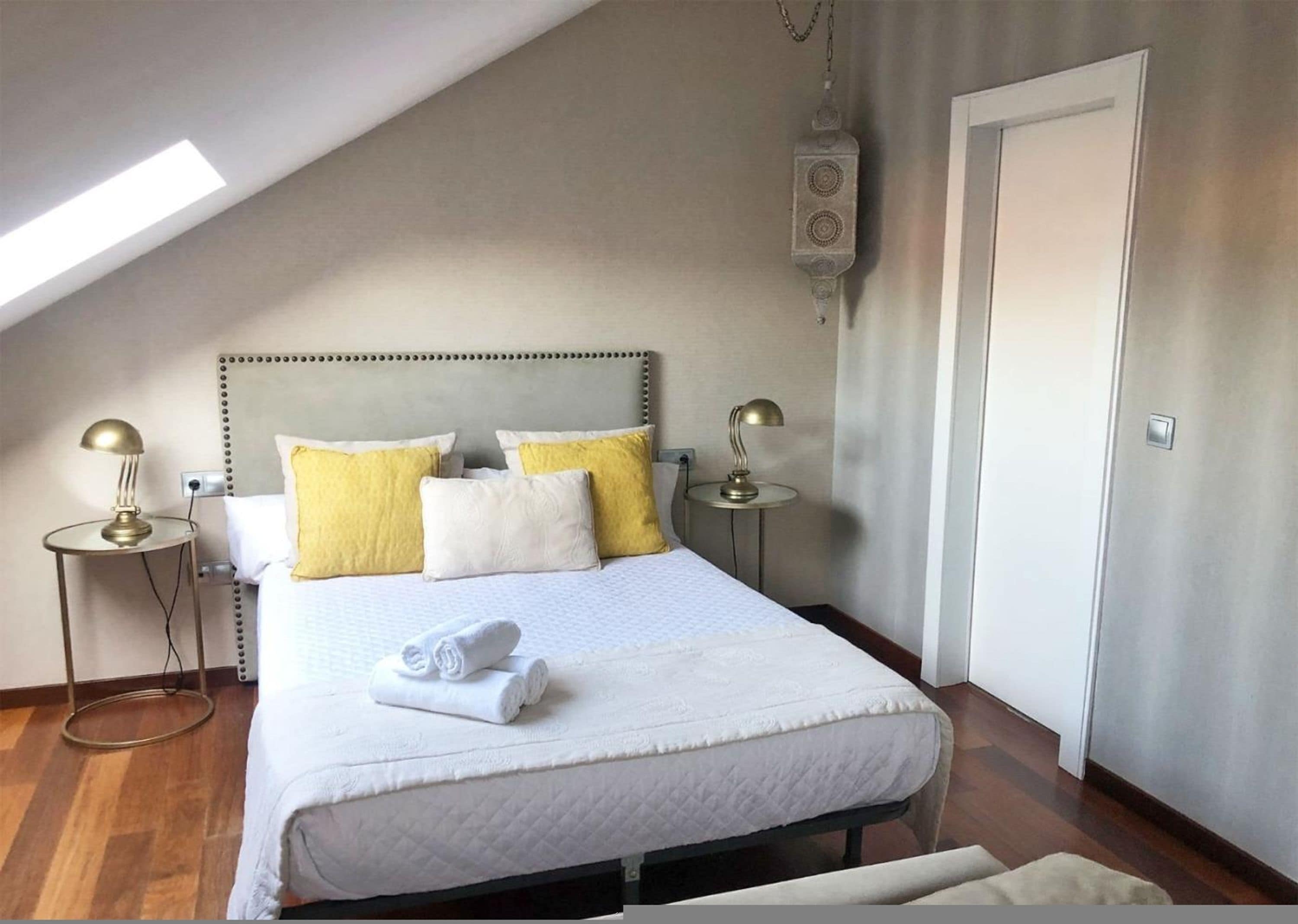 A neatly arranged bedroom with a bed, two bedside tables, and a hanging light fixture.