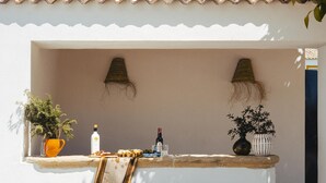 A bar area with a rustic wooden counter, two stools, and potted plants. - Campi a Villa Alicia (Porcuna)